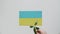 Tank stands on flag of Ukraine. Child hand takes vehicle, puts green plant.