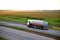 Tank truck driving on highway. Transportation of liquid goods. Metal chrome cistern tanker with petrochemicals products. Oil and