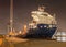 Tanker with a large crane at illuminated embankment at night, Port of Antwerp