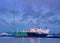 Tanker moored at petrochemical production plant with windmills at twilight, Port of Antwerp, Belgium