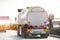 Tanker truck driving on the highway, white empty color, rear view, among other cars in the city