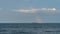 Tankers on sea horizon and short wide rainbows, clouds in sky