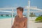 Tanned attractive man near ocean in swimming wear at tropical beach at island luxury resort