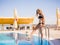 Tanned beach girl walking in the pool on a resort background. Holiday concept. Copy space.