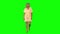 Tanned blond woman is calmly walking and smiling on green screen. Chroma key, 4k shot. Front view.
