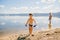 Tanned boy of three years in swimming trunks plays on the lake in the summer, summer vacation