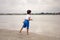 tanned child boy in blue shorts and a white T-shirt walks barefoot the lake in summer