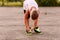 Tanned child tying shoelaces on sports shoes in the summer