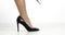 Tanned female legs in black shoes with high heel on a white background.