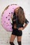 Tanned girl in a black jacket licked big donut.