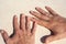 Tanned hands of newlyweds with gold rings on ring fingers on white sand as a symbol of wedding travel