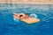 Tanned and happy boy floating on an inflatable mattress in an outdoor pool