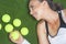 Tanned Happy Female Sportswoman Lying on Artificial Grass Surface With Tennis Balls