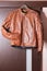 Tanned Leather Stylish Motorcyclist Jacket Hinged Over Sliding Door Holder