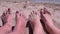 Tanned Red Bare Feet of Mother and Child in Sand Lies on a Sandy Beach