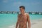 Tanned sexy male model enjoying sun bathing at tropical sandy beach at island luxury resort