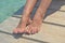 Tanned well-groomed legs with pedicure on a turquoise sea background.