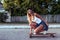 Tanned woman, fashionable and stylish girl rides on the way to the skateboard, longboard. White bodysuit swimsuit