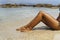 Tanned woman legs in the shore of paradise empty beach