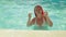 Tanned woman with pigtails dancing in the pool.
