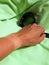 Tanned womans hand with sports watch taken off with a clear and visible tan line from smartwatch on green micro fiber towel. Rest