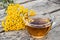 Tansy infusion in a glass cup on a wooden table. Tansy Herbal tea. Healing herbs