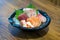 A tantalizing display of Japanese sashimi, elegantly served in a pristine bowl, resting on a rustic wooden table. Experience the