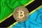 Tanzania flag, bitcoin gold coin on flag background. The concept of blockchain, bitcoin, currency decentralization in the country