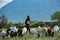 TANZANIA, NATRON LAKE - JAN 2020: Maasai boy shepherd with flock of sheeps and Ol Doinyo Lengai on background