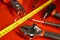 Tape measure, screwdriver, hammer, pliers and other tools lie on a red polished surface in a car repair shop. Devices for work of