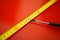 Tape measure and screwdriver-tap on the red polished surface in the auto repair shop. Performance of work