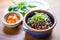 tapenade in a clay dish with a side of fresh basil