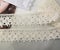 Tapes of ecru white guipure, beauty silk lace fabric on light background