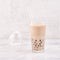 Tapioca pearl ball bubble milk tea, popular Taiwan drink, in drinking glass with straw on marble white table and wooden tray,