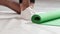 Tapping foot athletic man standing on knee on the floor next to unwinded roll mat, cleaning place after sports. Sportive