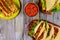 Taquitos, soft tortillas and salsa on wooden table