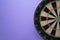 Target dart board on the purple table background, center point, head to target marketing and business success concept