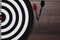 Target and two darts on wooden background