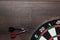 Target and two darts on wooden table