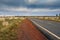 Tarmac road lead to nowhere in Australian desert in stormy cloud