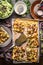 Tarte flambee or open vegetable pie with vegetables and salad on rustic kitchen table background with plates and tools, top view