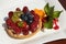 Tartlet with cheese cream, wild berries and kiwi