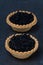 Tartlets with black caviar on a dark background