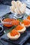 Tartlets with butter and red caviar and dill on a black wooden table.