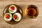 Tartlets with cream, strawberry and kiwi in brown saucer, cup with tea on wooden table. Top view