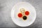 Tartlets filled with red and black caviar and cheese and dill salad on white plate against silver wooden background