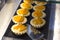 Tartlets with fresh peaches and arbicos on a black tray