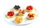 Tartlets with fruits and berries in a round plate on an isolated white background