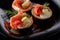 Tartlets with salmon , cream and a slice of lemon on a black plate.