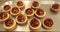 Tartlets on the table of a professional confectioner are decorated with apple-jelly